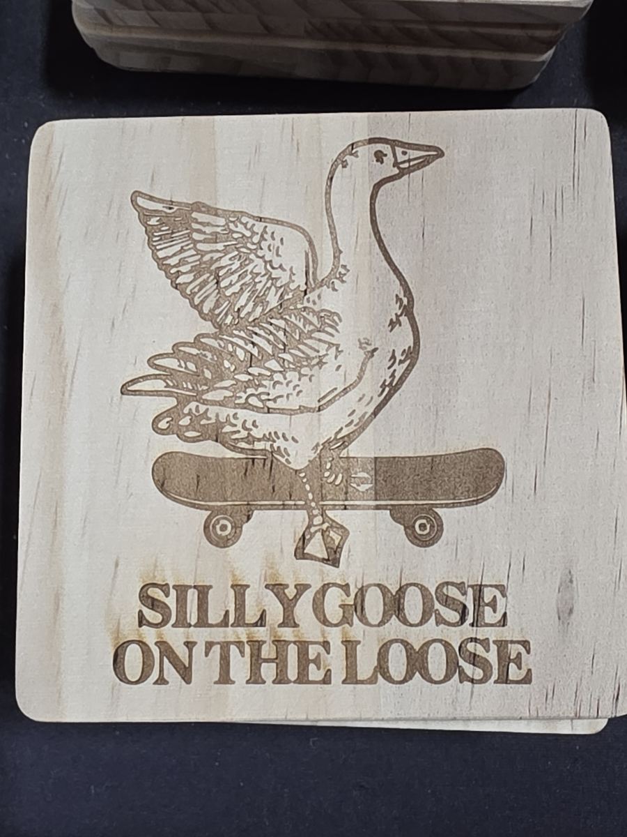 Wooden coaster with an engraved goose illustration